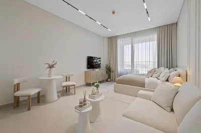 a white bedroom with a bed and a living room at Daniels Studio with Canal View at Marasi Drive in Dubai