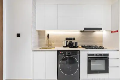 a white kitchen with a dishwasher and a stove at Daniels Studio with Canal View at Marasi Drive in Dubai