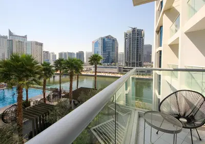 a balcony with palm trees and a view of a city at Dubai Dreams Pool & Canal View at Prive in Dubai