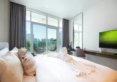 a bedroom with a white bed and a large window at Dubai Dreams Pool & Canal View at Prive in Dubai