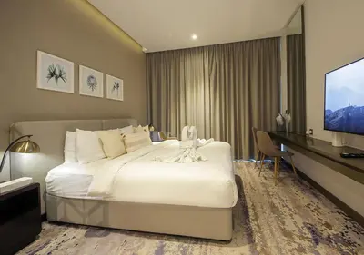 a hotel room with a bed and a flat screen tv at Dubai Dreams Pool & Canal View at Prive in Dubai