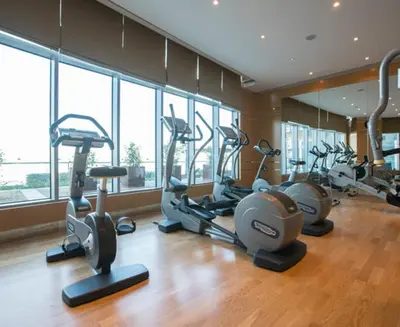 a gym with several exercise bikes in a room with windows at Dubai Dreams Pool & Canal View at Prive in Dubai