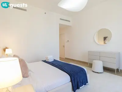 a white bedroom with a bed and a mirror at HiGuests - La Rive Living Classy 2BR with Balcony in Dubai