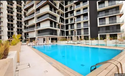 a swimming pool in front of a large apartment building at Modern Luxury Fully Furnished 1BH Apartment in Binghatti Luna JVC - Easy Access to JBR, Circle Mall & Dubai Hills Mall in Dubai