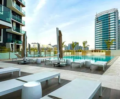a swimming pool with tables and benches next to a building at Modern Luxury Fully Furnished 1BH Apartment in Binghatti Luna JVC - Easy Access to JBR, Circle Mall & Dubai Hills Mall in Dubai