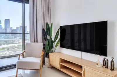 a living room with a large television and a chair at GuestReady - Luxury Oasis in Business Bay in Dubai