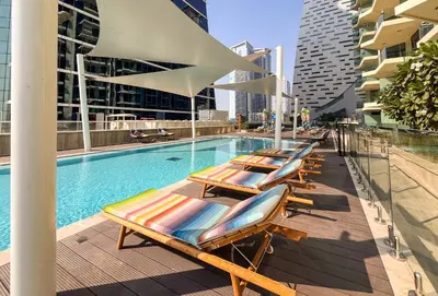 a row of lounge chairs next to a swimming pool at Upscale 1BR Luxury Apt in Business Bay in Dubai