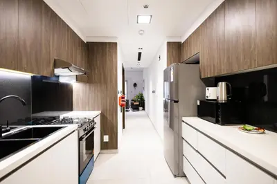 a kitchen with white counters and wooden cabinets at Spacious 2BR Apartment l Rooftop Pool l Gym in Dubai