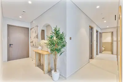 a hallway with white walls and a staircase with a potted plant at Luxury 4BR Full Burj khalifa & Fountain View, 1Gbps, PS5 in Dubai