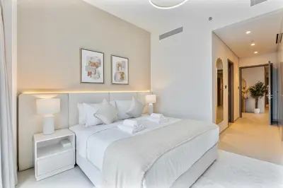 a white bedroom with a large white bed with two lamps at Luxury 4BR Full Burj khalifa & Fountain View, 1Gbps, PS5 in Dubai
