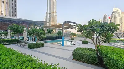 a garden with a pool and a umbrella in a city at Luxury 4BR Full Burj khalifa & Fountain View, 1Gbps, PS5 in Dubai