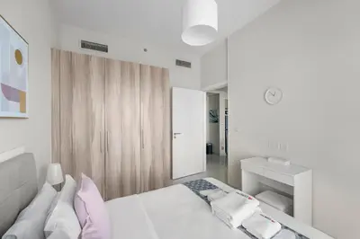 a white bedroom with a bed and a mirror at Modern 1BR at Golf Vita A in Damac Hills Near Golf in Dubai