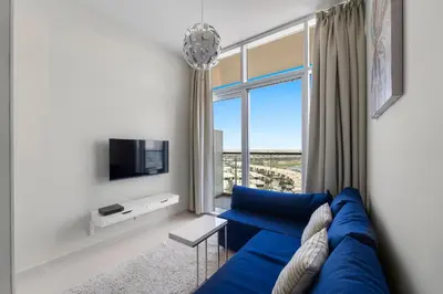 a blue couch in a living room with a window at Modern 1BR at Golf Vita A in Damac Hills Near Golf in Dubai