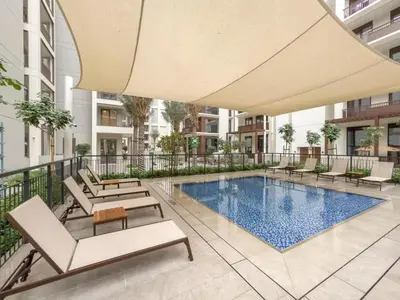 a swimming pool with lounge chairs and an umbrella at FAM Living - Modern 1BR at Orchid, Creek Harbour in Dubai