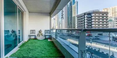 a woman sitting on a balcony with a view of a city at 8min Walk from JBR beach Stylish 1-Bedroom Apartment in Dubai Marina in Dubai