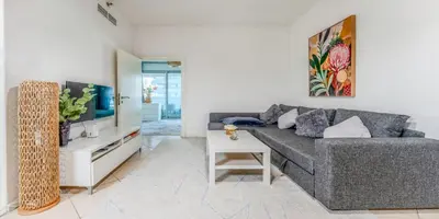 a living room with a gray couch and a tv at 8min Walk from JBR beach Stylish 1-Bedroom Apartment in Dubai Marina in Dubai