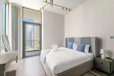 a white bedroom with a bed and a large window at Stylish 2BR in Royal MBL in Dubai