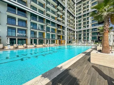 a large swimming pool with a palm tree in front of a building at Vibrant - 2BR - Exclusive Pool, Shared Gym in Dubai