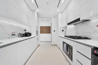a white kitchen with white counters and a stove at Vibrant - 2BR - Exclusive Pool, Shared Gym in Dubai