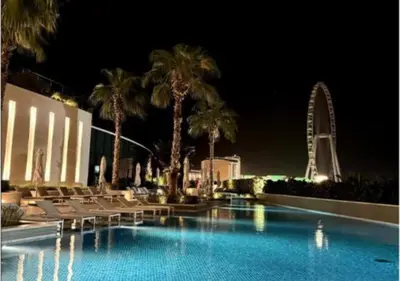 a swimming pool with chairs and palm trees at night at Modern Stay at The Address JBR in Dubai