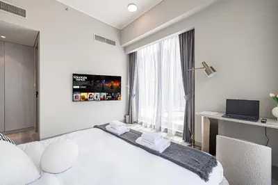 a white bedroom with a bed and a laptop on a desk at Stylish 1BR with Spacious Terrace Near Circle Mall in Dubai