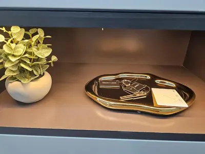 a gold tray with a key and a plant on a shelf at New Renovated Stylish 1 Br Dubai View 73 Floor in Dubai