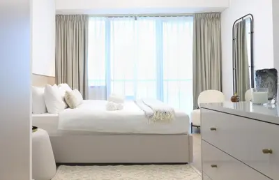 a white bedroom with a bed and a large window at New Renovated Stylish 1 Br Dubai View 73 Floor in Dubai