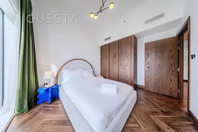 a bedroom with a large white bed and wooden cabinets at Emaar Beachfront - Sunrise Bay Tower 1, Dubai Marina in Dubai