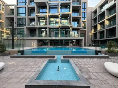 an apartment building with a swimming pool in front of a building at Brand New Designer Studio - Urban Retreat in JVC in Dubai