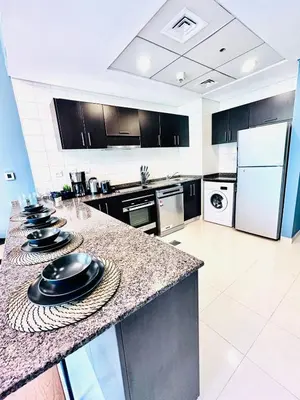a large kitchen with a counter with black appliances at Bright and Modern Condo in Dubai Marina in Dubai