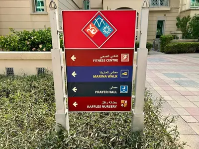 a sign in the grass in front of a building at Stylish Apartment - Dubai Marina in Dubai