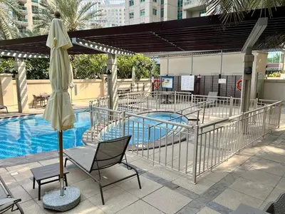 a pool with a table and a umbrella and a chair at Stylish Apartment - Dubai Marina in Dubai