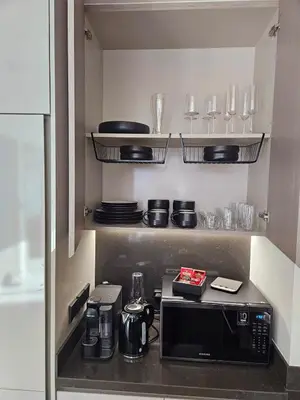 a kitchen with a microwave and some plates and glasses at Luxury Fully Furnished One Bedroom in Dubai
