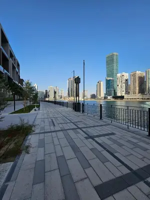 a sidewalk next to a body of water with a city at Luxury Fully Furnished One Bedroom in Dubai