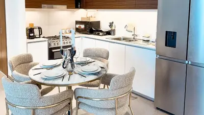 a kitchen with a table with chairs and a refrigerator at Luxury 2BHK & Lagoon view in Dubai