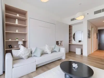 a living room with a white couch and a table at TRPS - Carson Tower B, DAMAC Hills - Brand New Luxury Studio Apartment in Dubai