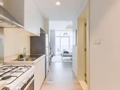 a white kitchen with a stove and a sink at TRPS - Carson Tower B, DAMAC Hills - Brand New Luxury Studio Apartment in Dubai