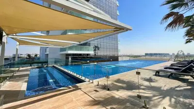a swimming pool in front of a building at TRPS - Carson Tower B, DAMAC Hills - Brand New Luxury Studio Apartment in Dubai
