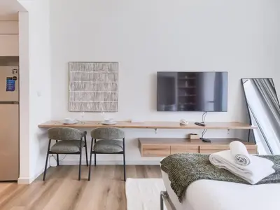 a bedroom with a desk and a tv on a wall at TRPS - Carson Tower B, DAMAC Hills - Brand New Luxury Studio Apartment in Dubai