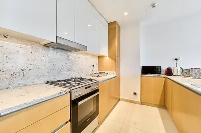 a kitchen with white cabinets and a stove top oven at Chic 2BR in Mulberry with Dubai Hills Park Views in Dubai