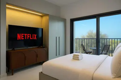 a bedroom with a bed and a tv and a balcony at Sleek New Studio in Meydan, Fully Equipped and Spacious in Dubai