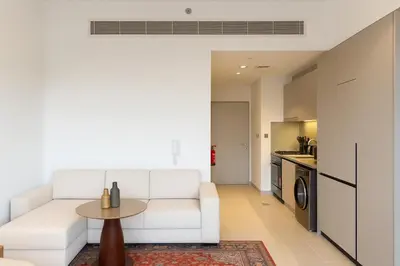 a living room with a white couch and a table at Sleek New Studio in Meydan, Fully Equipped and Spacious in Dubai