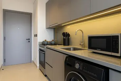 a kitchen with a sink and a microwave and a dishwasher at Sleek New Studio in Meydan, Fully Equipped and Spacious in Dubai