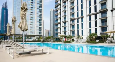 a pool with chairs and umbrellas next to buildings at Luxury 3BR Downtown Apt with Burj Khalifa, Dubai Mall & Opera House Views in Dubai