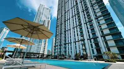 a pool with chairs and umbrellas in front of a tall building at Luxury 3BR Downtown Apt with Burj Khalifa, Dubai Mall & Opera House Views in Dubai