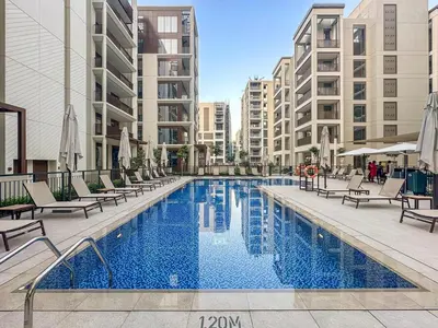 a large swimming pool with chairs and buildings at Family 2BR Near Creek, Shops, Dining & Top Attractions in Dubai