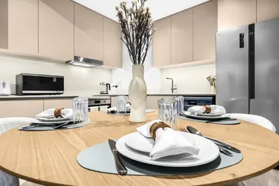 a kitchen with a wooden table with plates and utensils at Family 2BR Near Creek, Shops, Dining & Top Attractions in Dubai