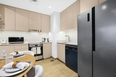 a kitchen with a table and a refrigerator at Family 2BR Near Creek, Shops, Dining & Top Attractions in Dubai