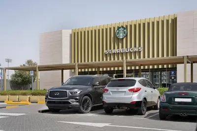 two cars parked in a parking lot in front of a store at Studio Aura at Dubai Sports City in Dubai