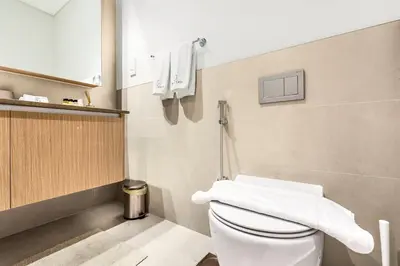 a bathroom with a toilet with white towels on the wall at FIRST CLASS 2BR Design Meets Comfort in Dubai